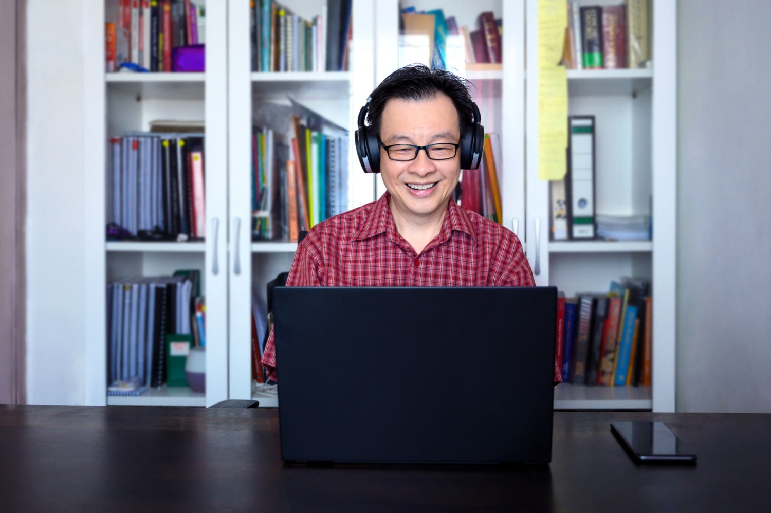 A mid-adult Asian businessman having video conference with his client on laptop at home office